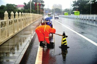 环卫工人冒雨清理桥梁上的排水孔