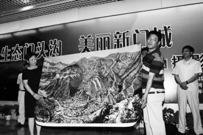 　　图为摄影作者李长山（右）将《雪浴山村》摄影作品赠送爨柏景区。