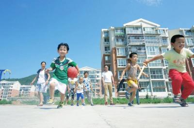 图为放暑假的孩子们在小区健身广场上玩耍。