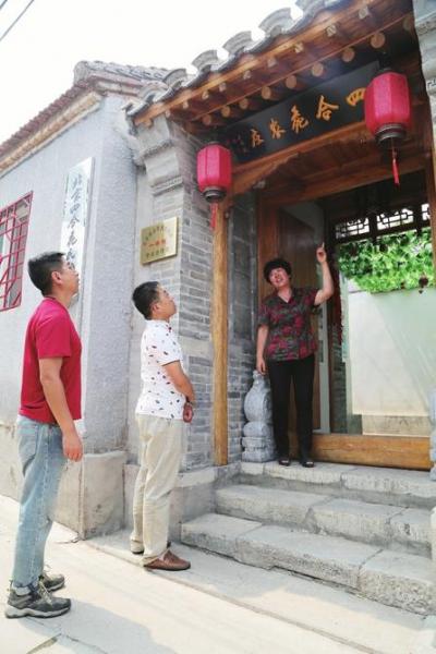 小院主人向游客介绍中式门楼