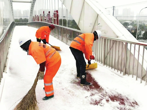 ▲养护工人清理过街天桥上的积雪